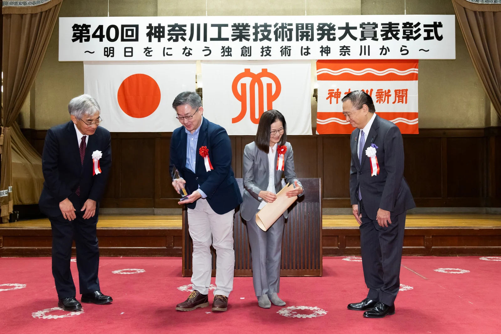 第40回 神奈川工業技術開発大賞 表彰式の様子。「第40回 神奈川工業技術開発大賞表彰式」と書かれた横断幕の前で、賞状が手渡されている。
