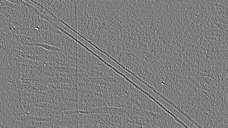 鋼板の 3D Surface。斜めに走る 2 本の平行な擦り疵が、灰色の面に浮かび上がっている。